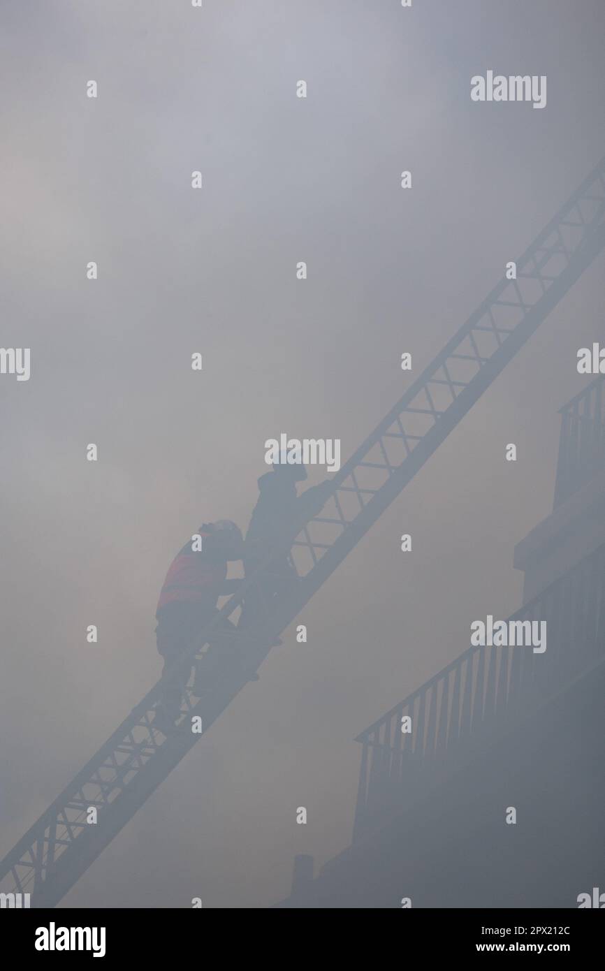 French riot police and firefighters on the big ladder extuinguish a ...