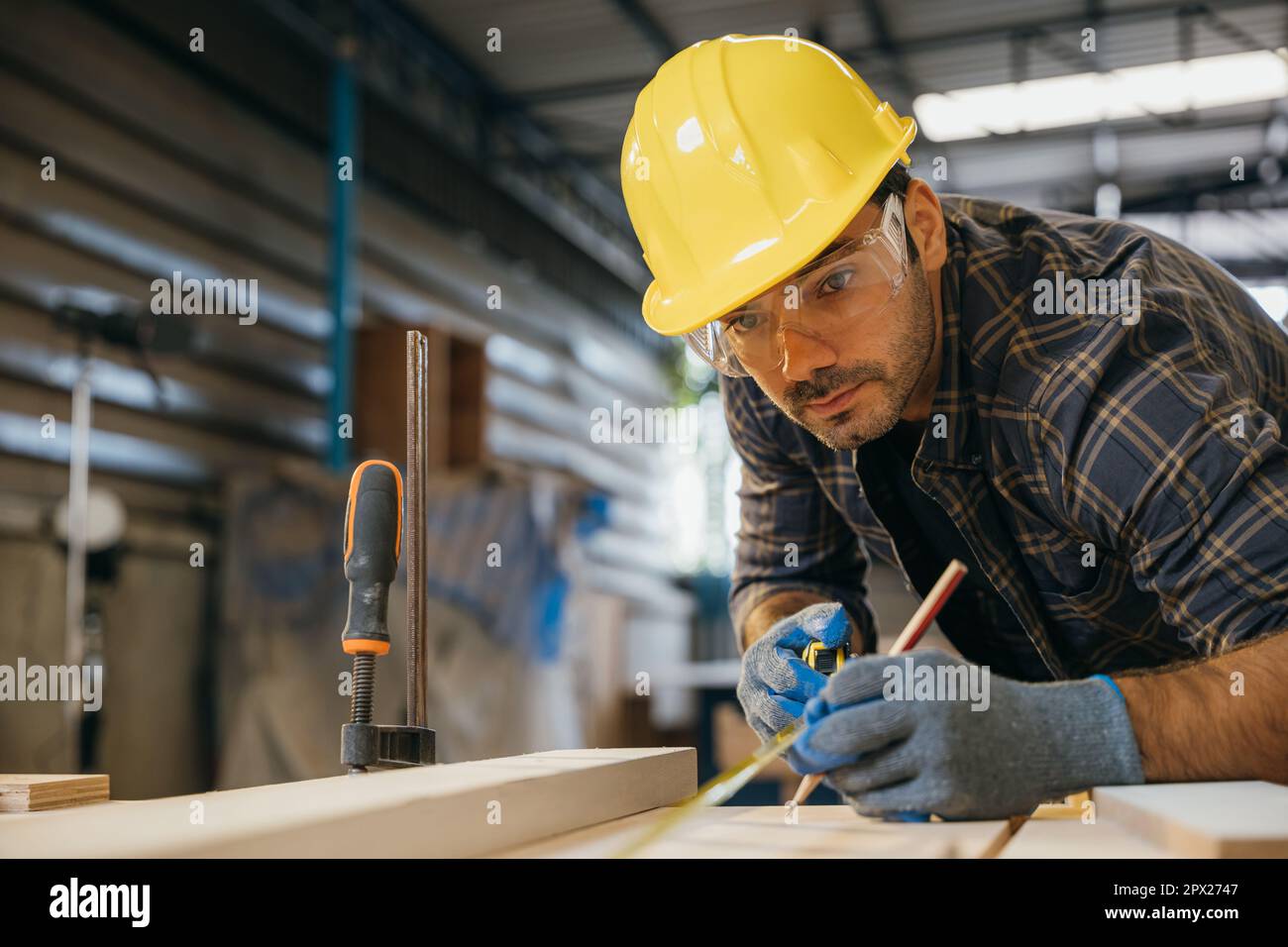 Carpenter man wear gloves during working using tape measure and pencil