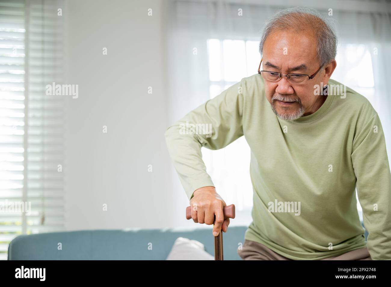 Asian Old man with eyeglasses typing to stand up from sofa with walking