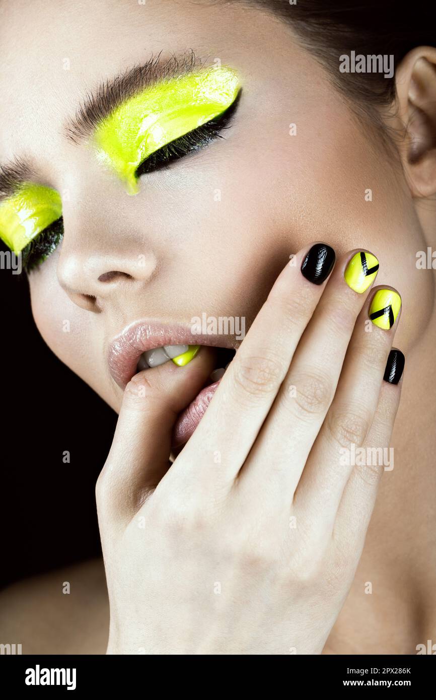 Close-up portrait of girl with yellow and black make-up, creative nail art disign. Beauty face. Photo shot in studio Stock Photo