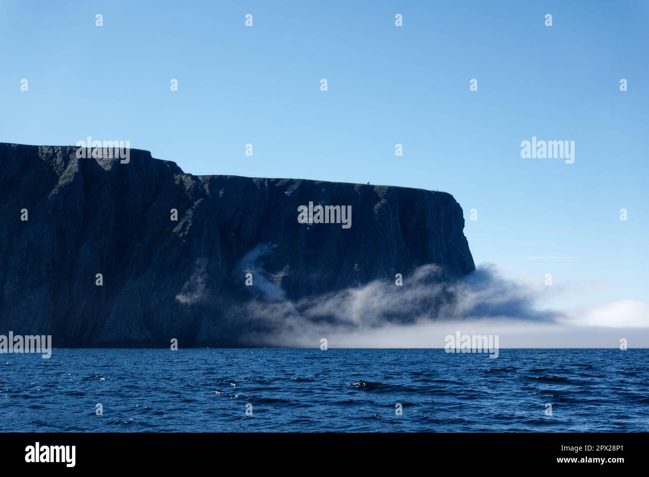 The northernmost tip of Europe large rock cliff of North Cape or Nordkapp on summer day with dramatic sea fog rising on Mageroya island in Finnmark in Stock Photo