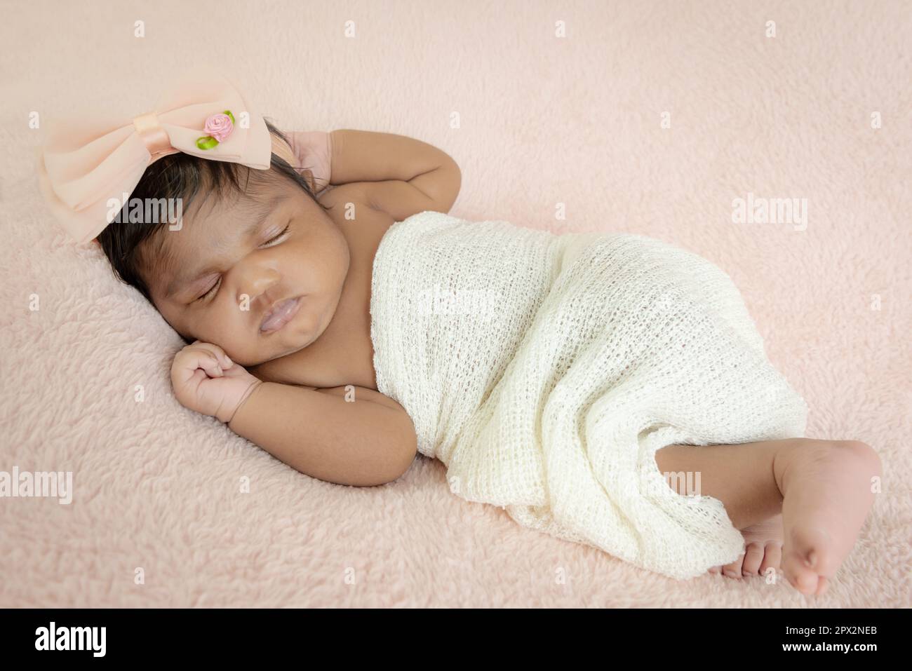 Newborn baby girl Indian studio set up soft blanket pink headband Stock Photo