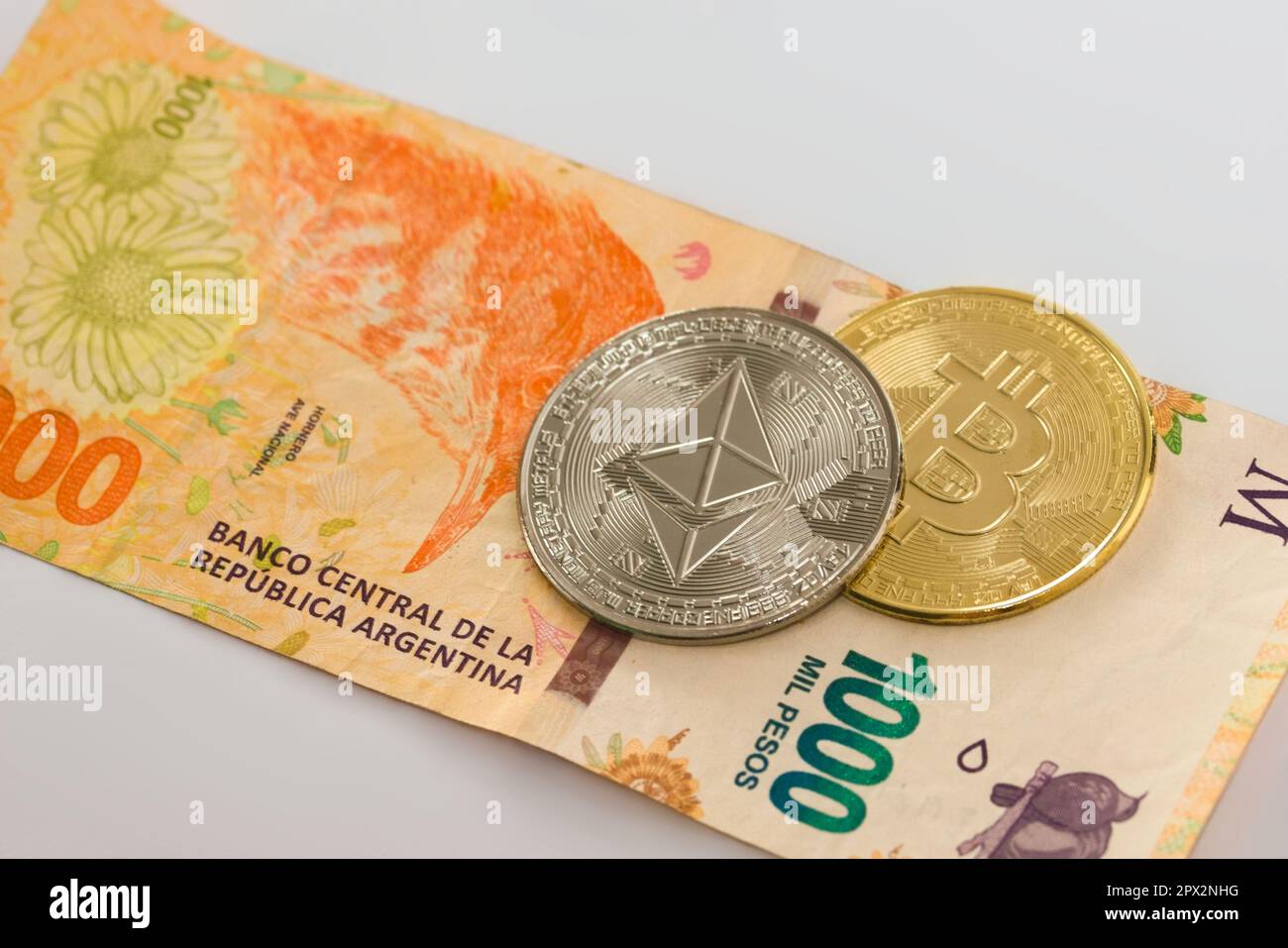 Physical Bitcoin and Ethereum coin over a thousand argentinian pesos bill  on white background. Cryptocurrency exchange, investment concept Stock  Photo - Alamy