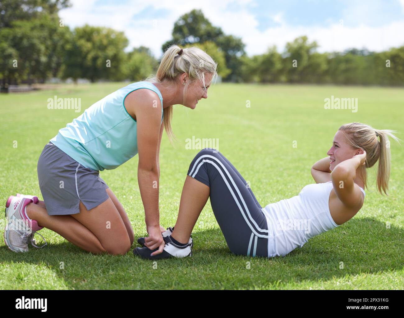 Just one more...A young woman doing crunches with the help of a trainer