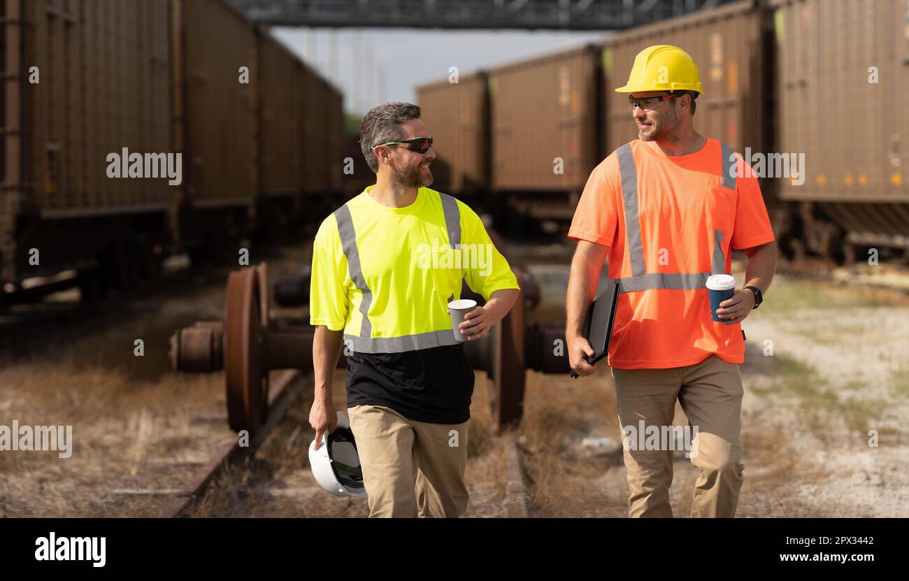 Railway employee and boss. Railway men in safety vests walking on