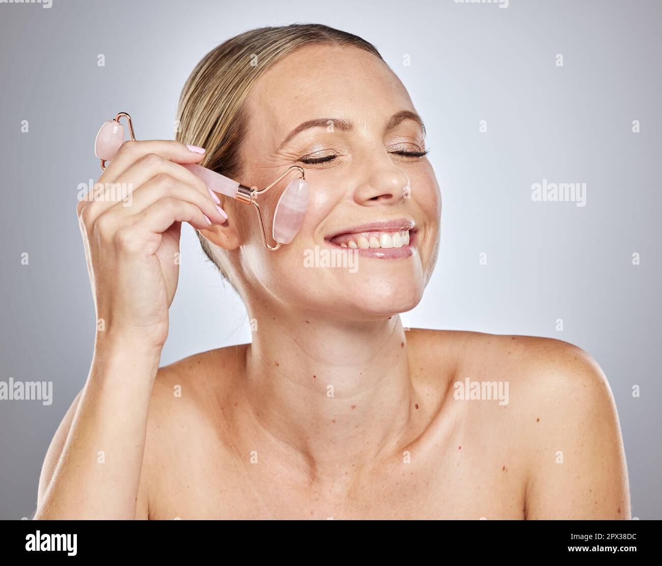 Woman, crystal and face skincare beauty with smile and exfoliate in studio for health, glow and cosmetics. Model happy, skin wellness and cleaning for Stock Photo