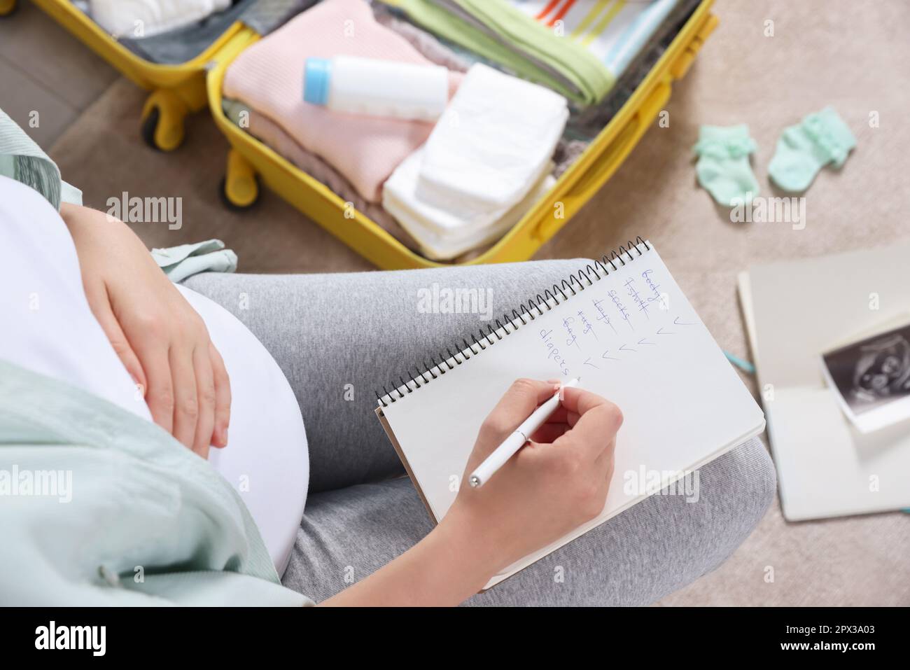 Pregnant woman preparing list of necessary items to bring into ...