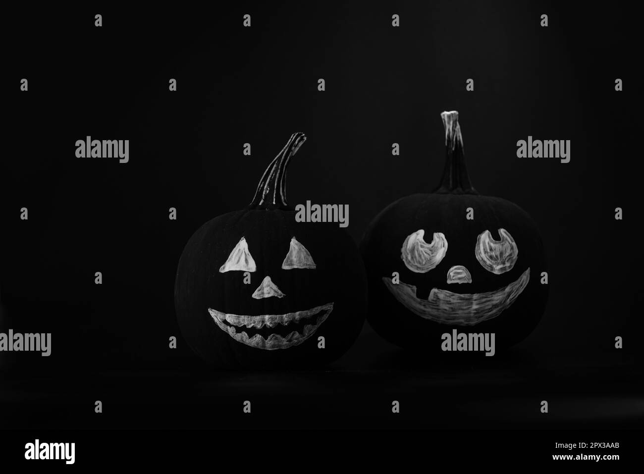 Halloween celebration. Pumpkins with drawn faces on table in darkness Stock Photo