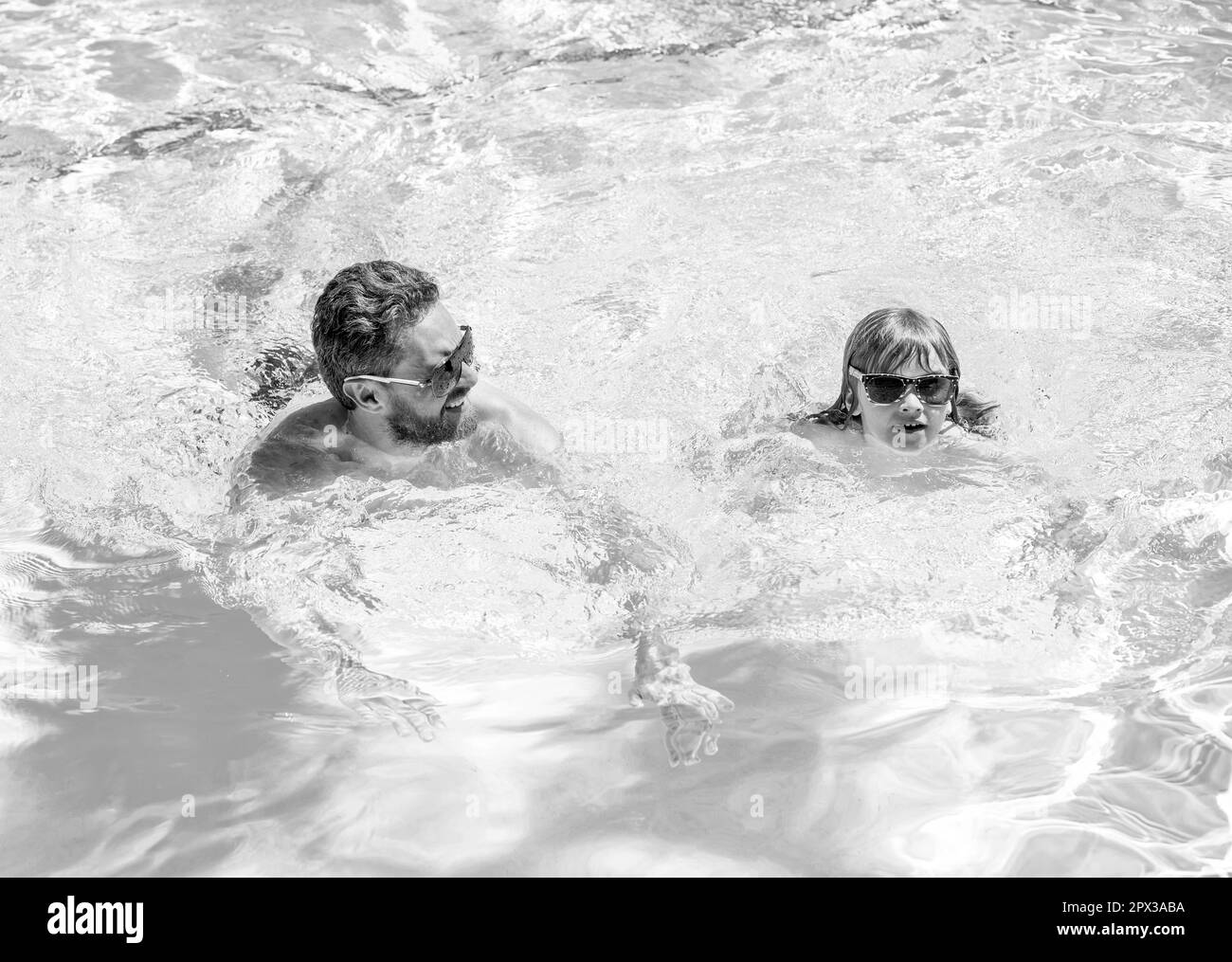father and son wear glasses in swimming pool water. daddy with kid boy on spa resort Stock Photo