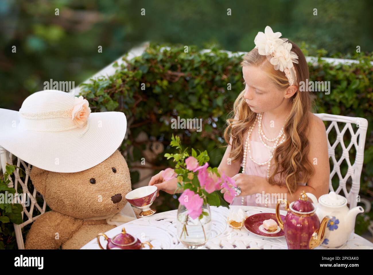 Tea with Teddy. A little girl sitting outside having a tea party with ...