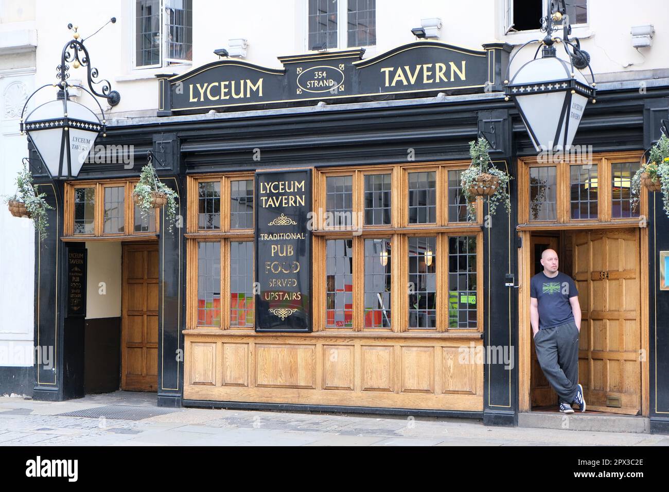 London, UK. The man wearing a Union Jack t-shirt leans on the door frame at the front of the Lyceum Tavern in the Strand. Stock Photo