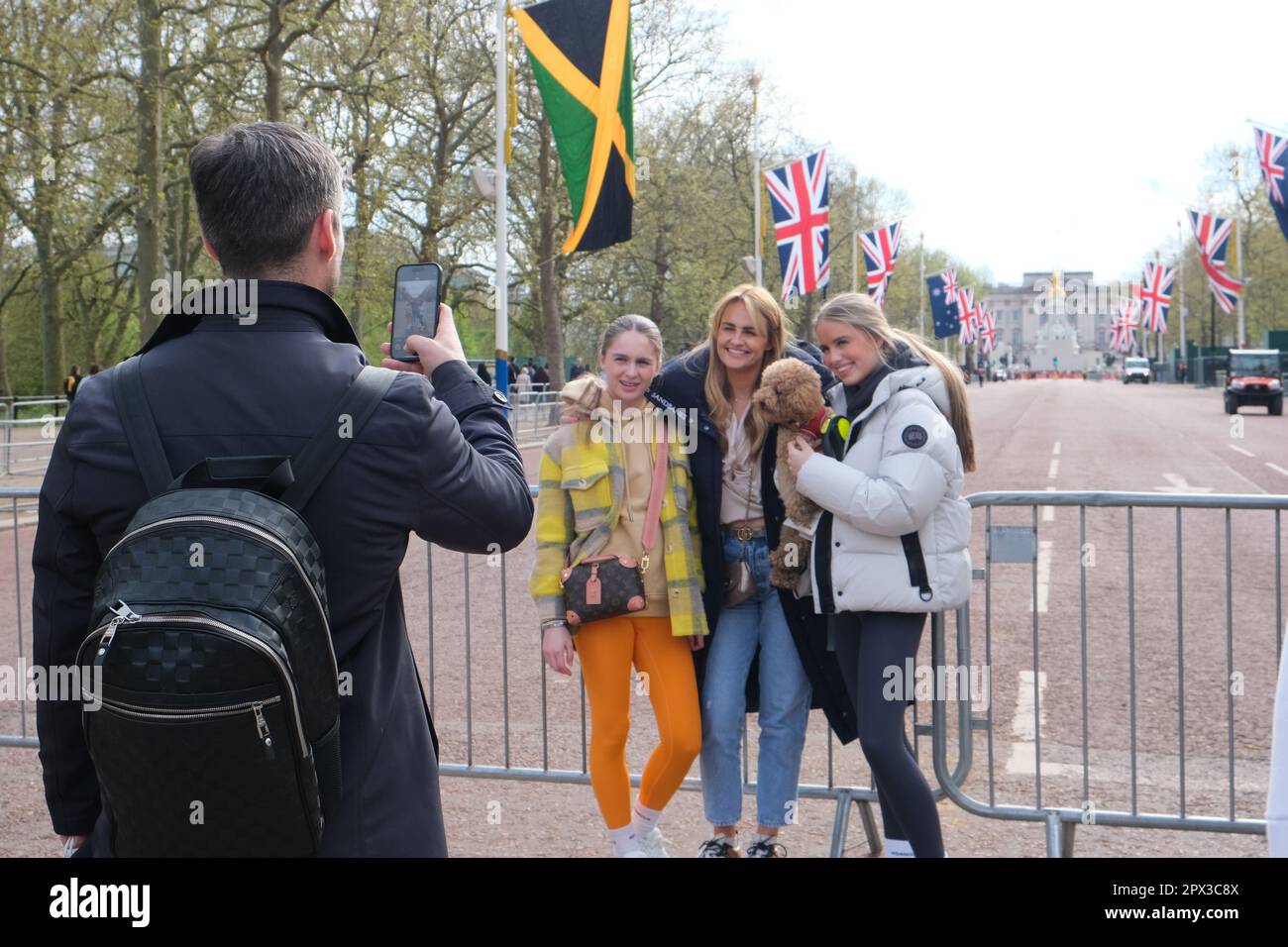 London, UK. Tourists take a photo in the Mall, decorated with Union Jacks and the commonwealth flags ahead of the King's Coronation. Stock Photo