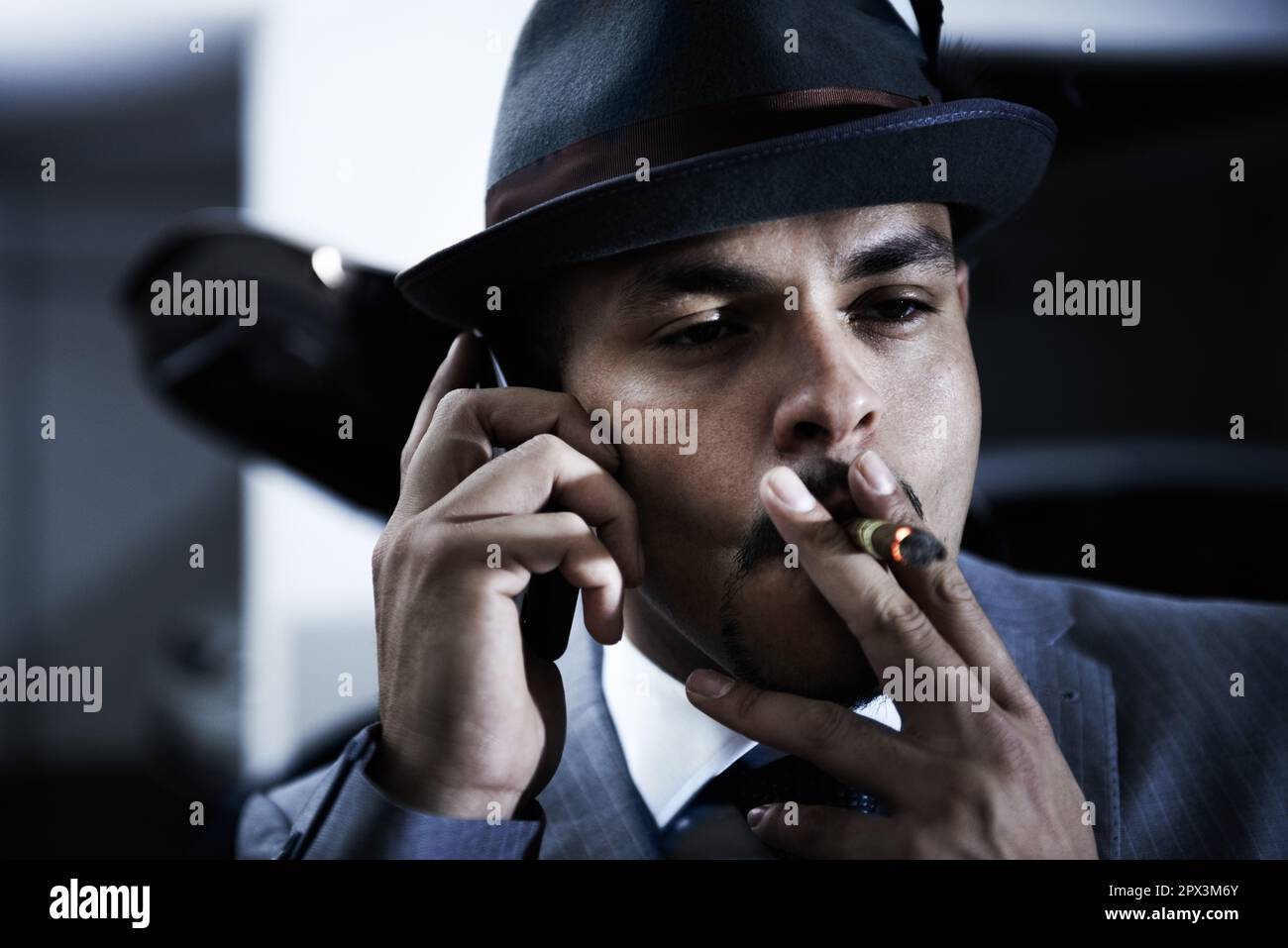 We got him. An arrogant mobster taking a drag of his cigar while talking on  his cellphone Stock Photo