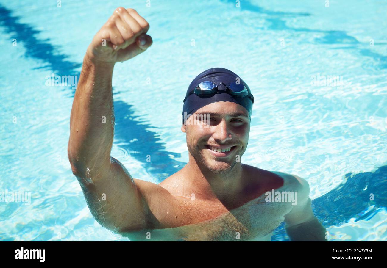 Winning. A handsome young swimmer wearing goggles and a swimming cap. Stock Photo