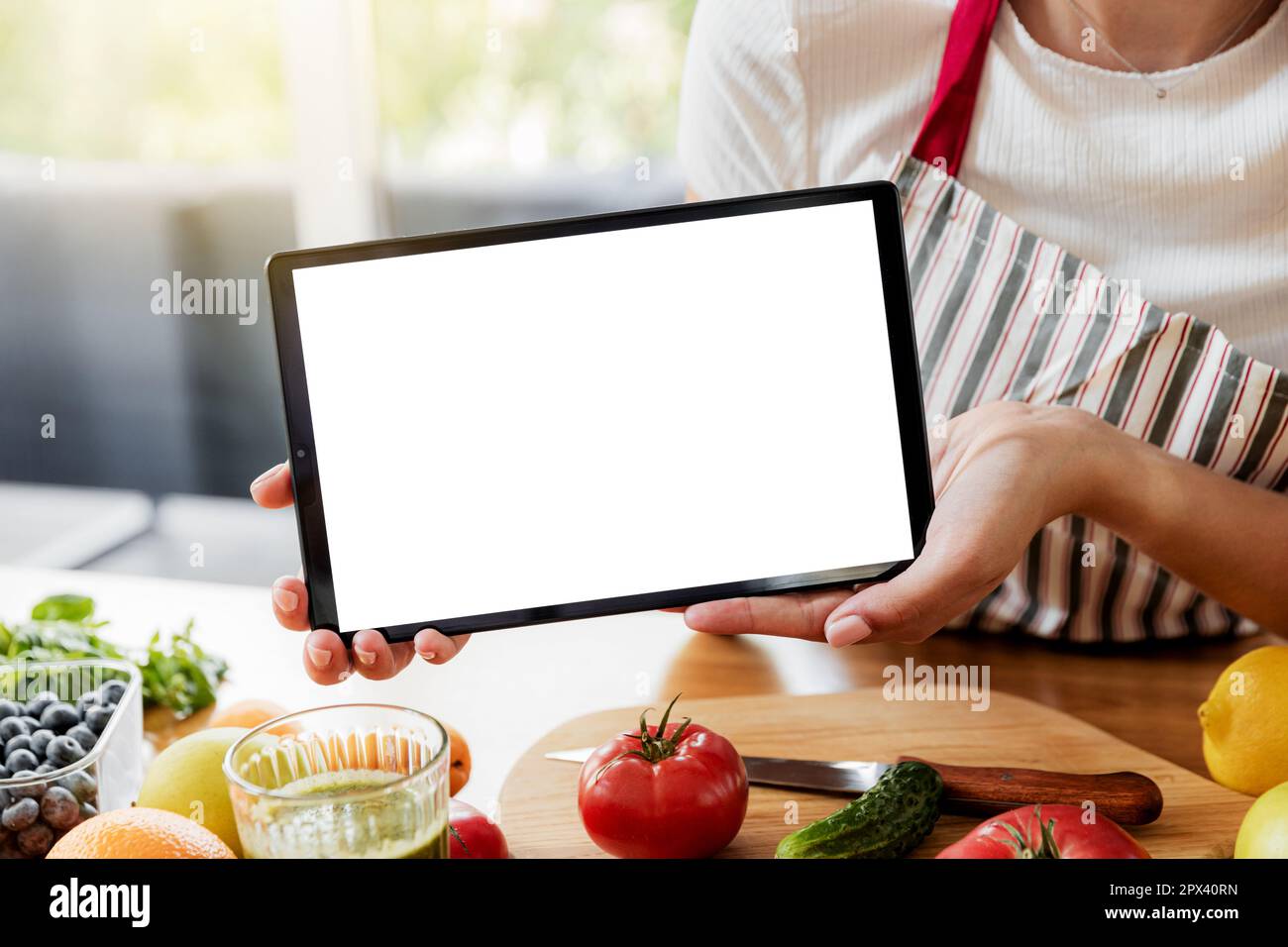 Woman hands showing digital tablet white empty blank screen mockup at kitchen. Chef using pc, present online grocery food shopping on computer. Delive Stock Photo