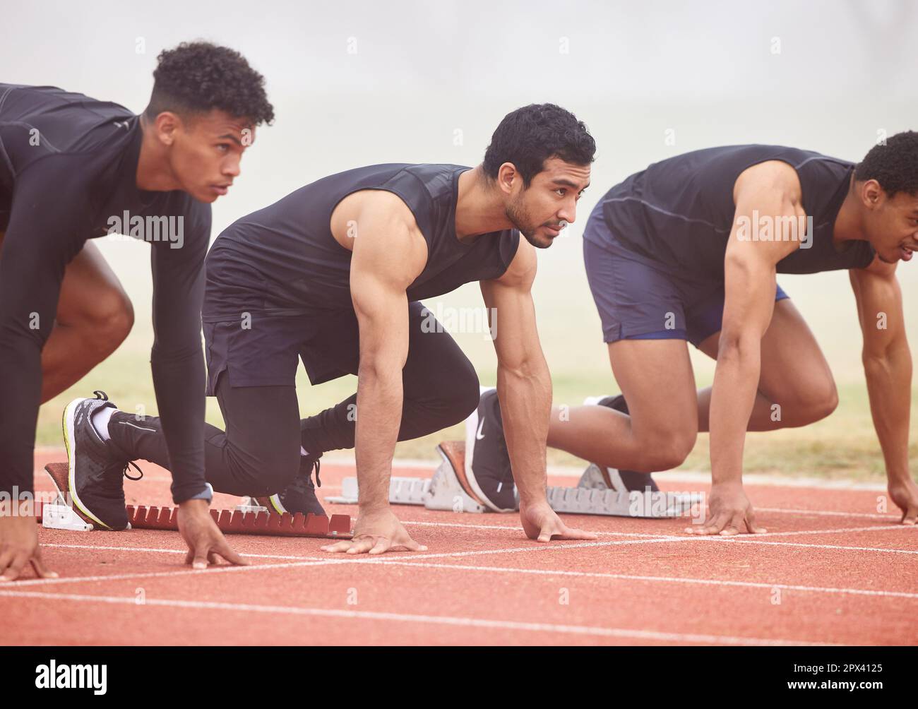 Ready to get started. three handsome young male athletes starting their race on a track Stock Photo
