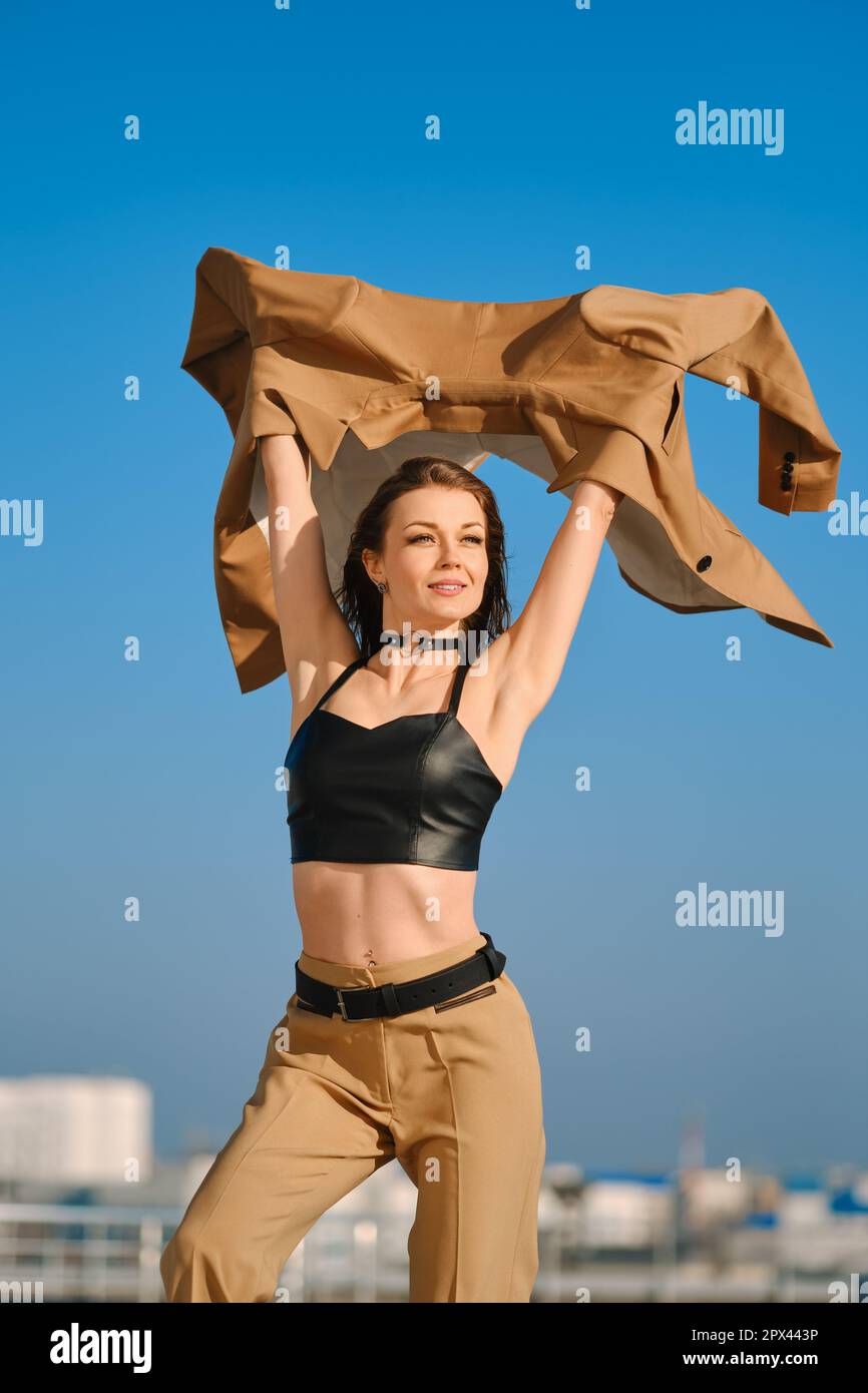 Street fashion, women casual and trendy outfit. Woman in pantsuit, leather tank-top and rough boots outdoor. Stock Photo