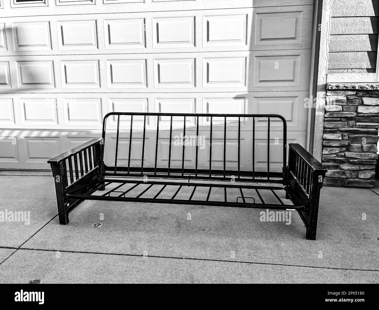 futon and frame on the sidewalk driveway of a house for free pickup