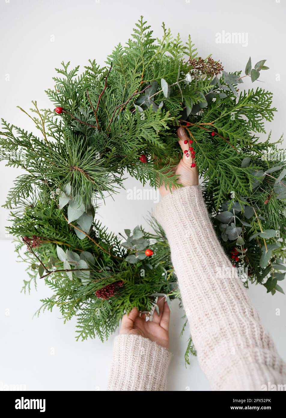 Stylish Christmas wreath for the interior, hang the wreath on the door. Handmade, the girl holds a freshly made wreath in her hands. The atmosphere of Stock Photo