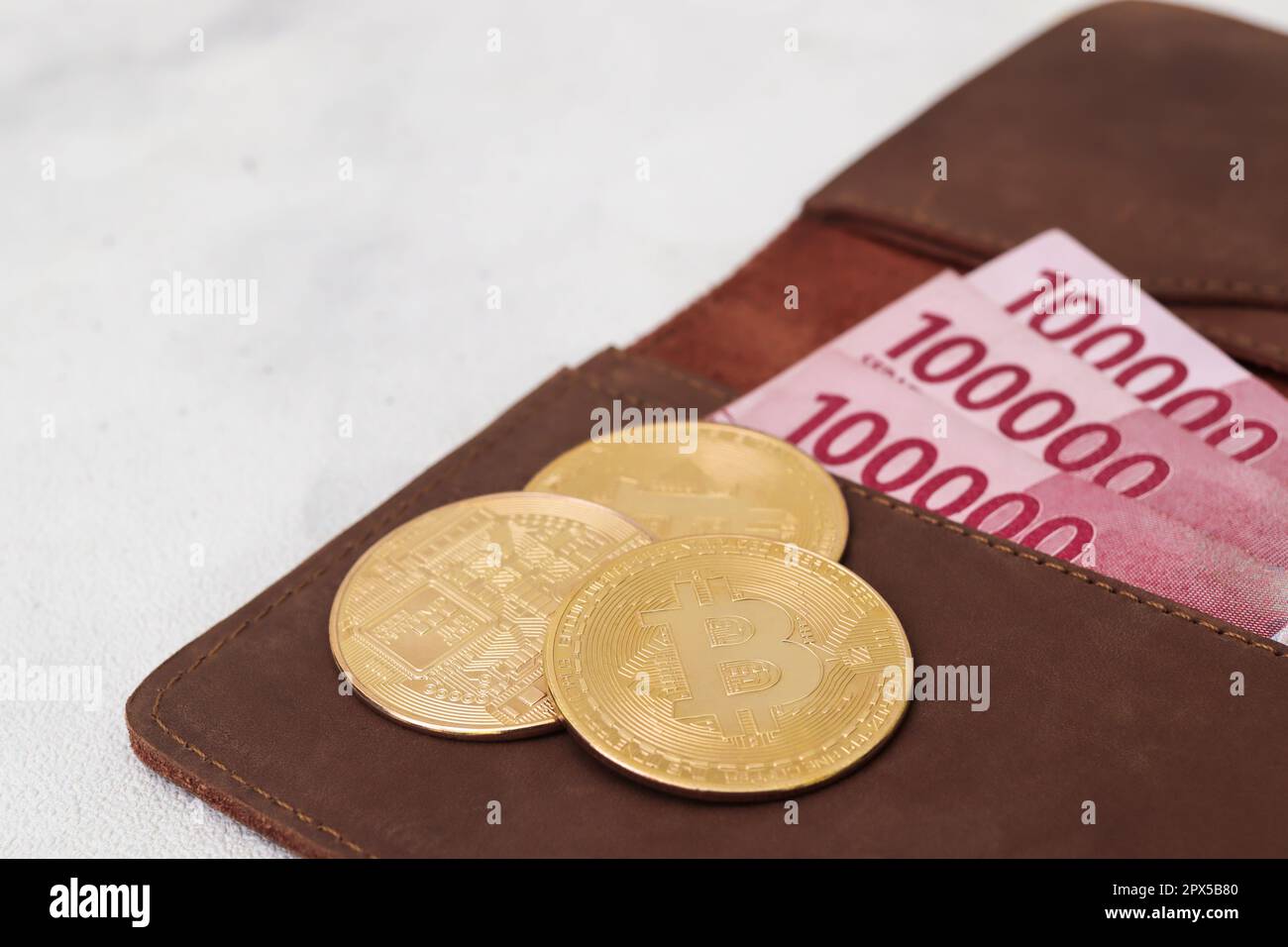 Bitcoin with one hundred thousand rupiah banknote on leather wallet.  Cryptocurrency trading concept Stock Photo - Alamy
