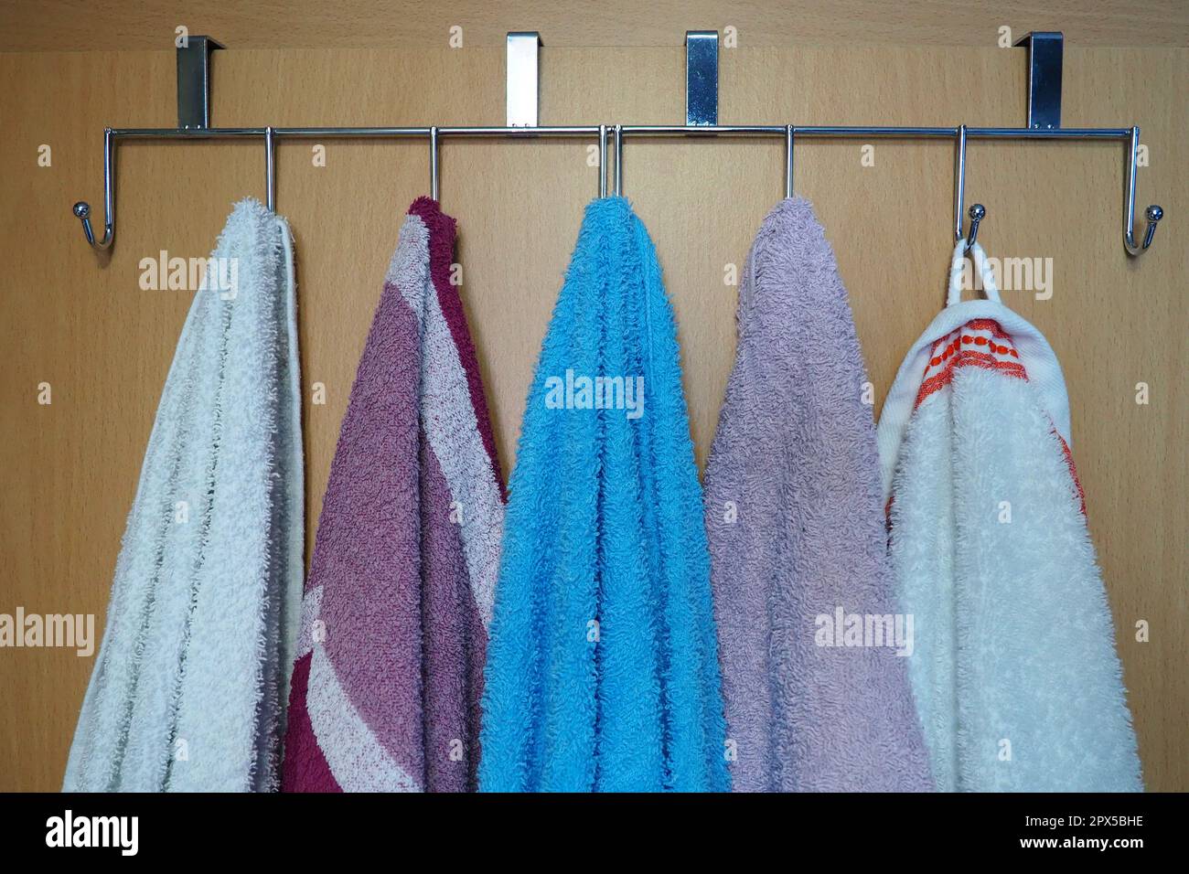 White, blue, pink towels hanging from metal hooks attached to the