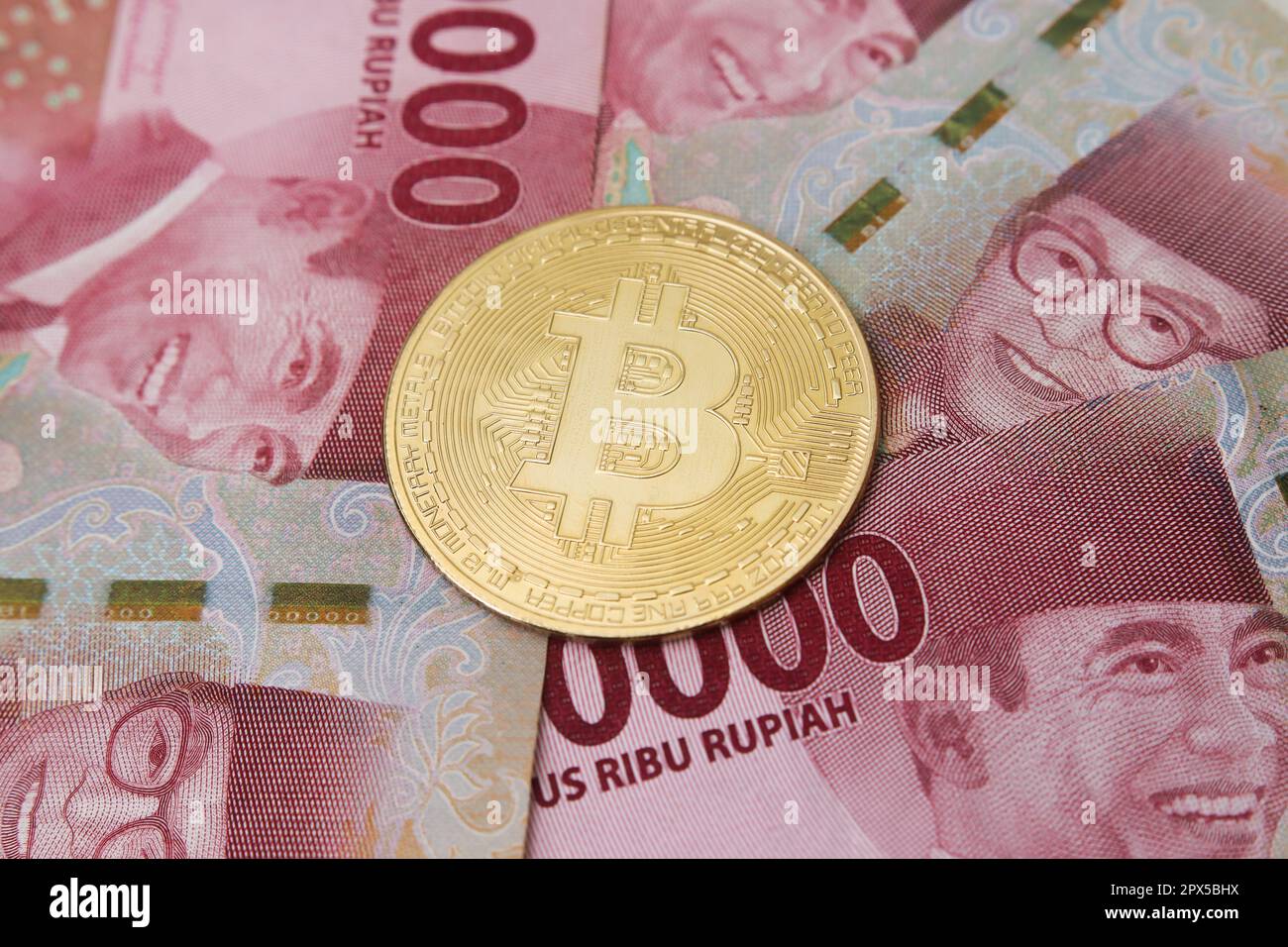 Bitcoin placing on the top of one hundred thousand rupiah bank note