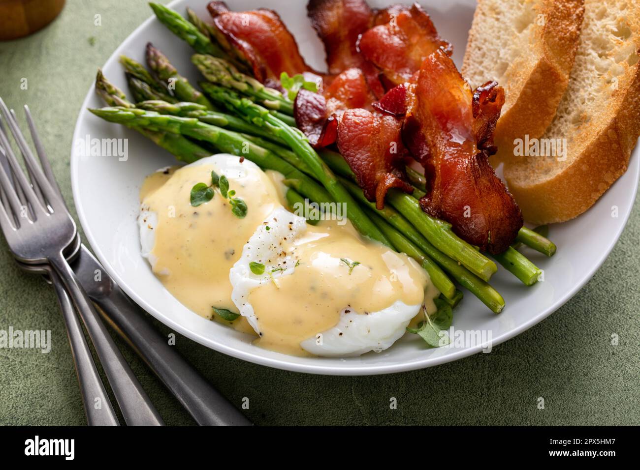 Healthy breakfast with poached eggs, bacon and asparagus served with hollandaise sauce Stock Photo