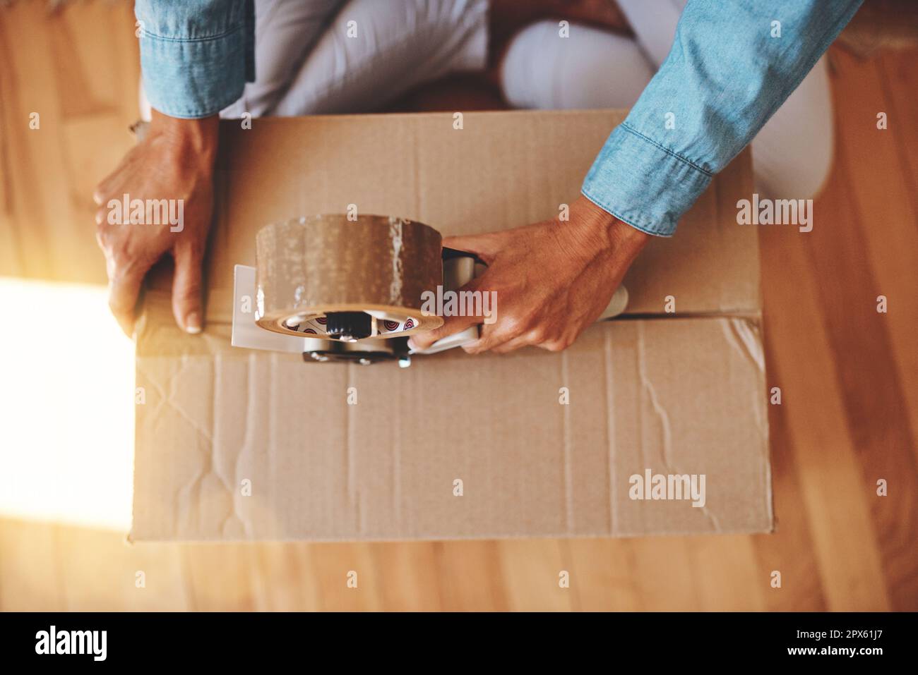 The final box. a woman sealing a box with adhesive tape at home Stock