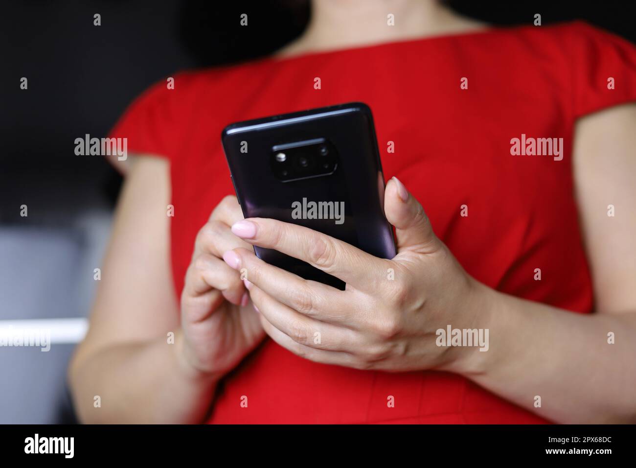 Woman in red dress using smartphone, mobile phone in female hands close up. Concept of online addiction, sms, social media Stock Photo