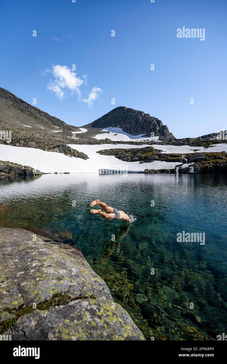 Young man jumps into a mountain lake, Skalavatnet, ascent to the summit of  Skala, Norway Stock Photo - Alamy