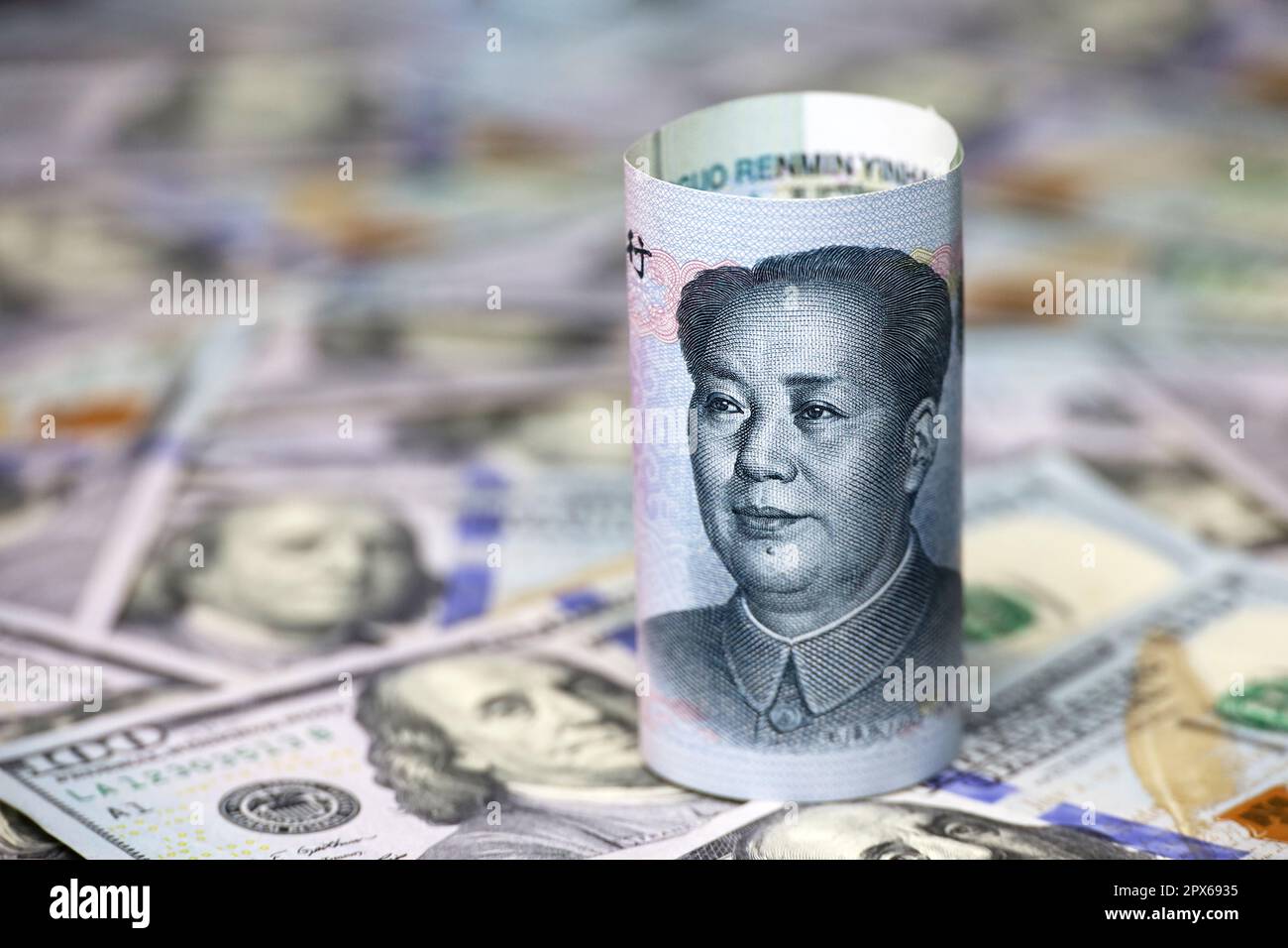 Chinese yuan banknote rolled up on US dollars background. Concept of