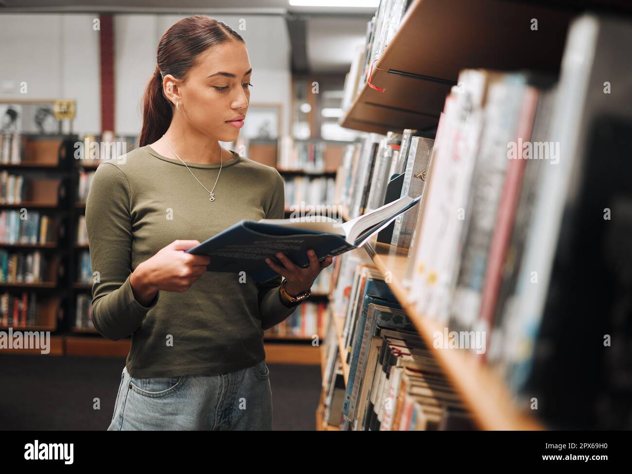 Black woman reading book in a library for education, studying and