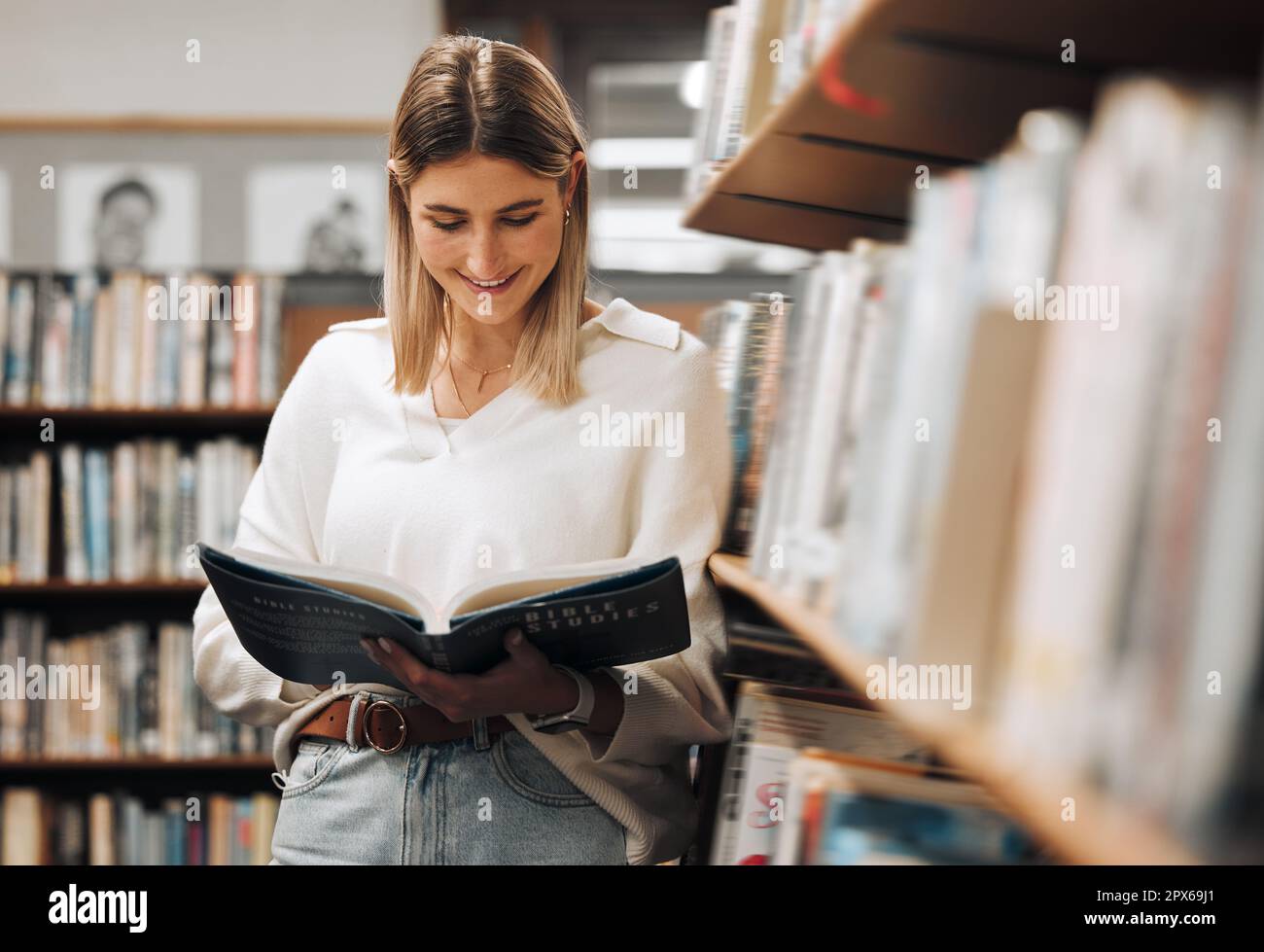 Happy, reading or student in library for books, educational knowledge or research for learning or assessment. School girl, college or university stude Stock Photo
