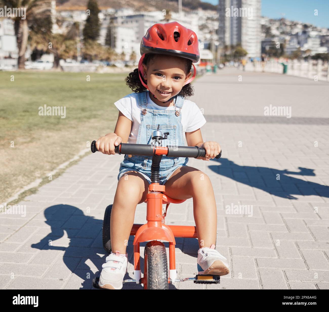 Portrait, girl child and cycling on sidewalk, learning to ride bike or