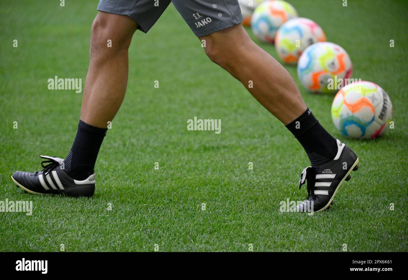 Coach with Adidas Copa Mundial sports shoe, logo, runs past Adidas Derbystar match ball, match balls, lying on grass, Mercedes-Benz Arena, Stuttgart Stock Photo