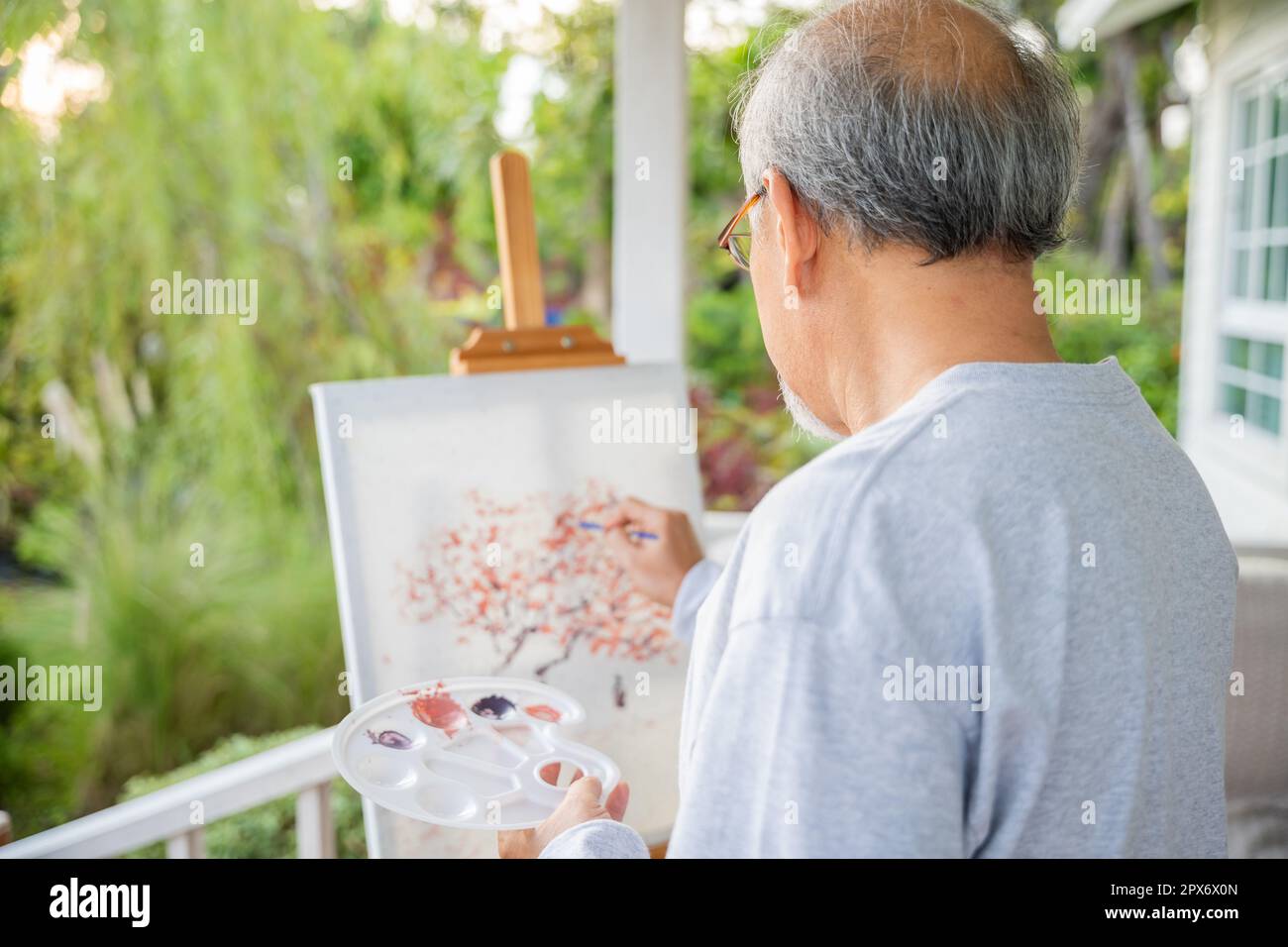 Lifestyle Asian senior old man painting picture artwork using brush and