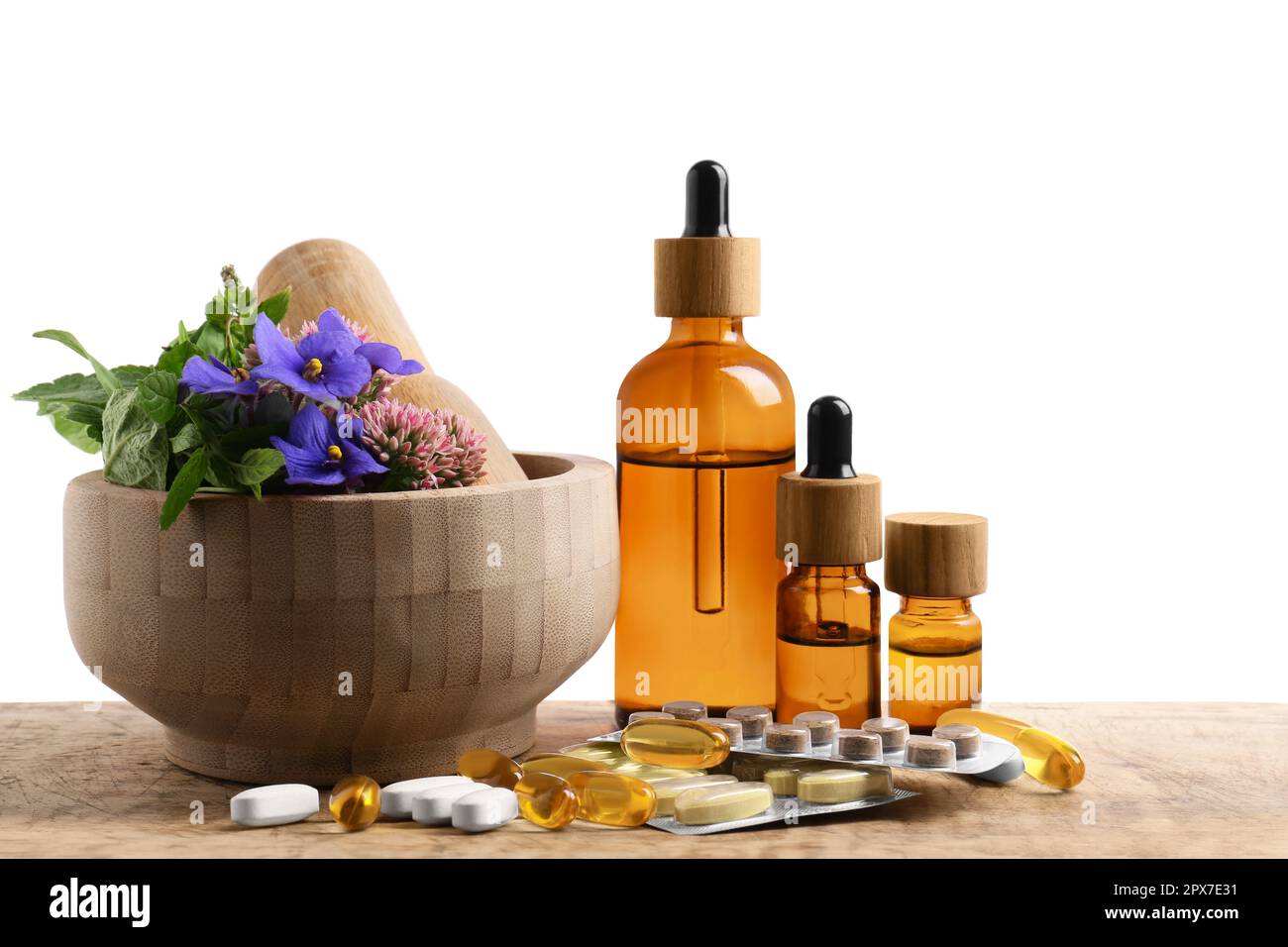 Mortar with fresh herbs, extracts and pills on white background Stock