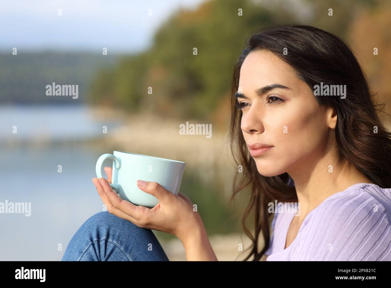 Smiling woman with coffee cup sitting on jetty stock photo