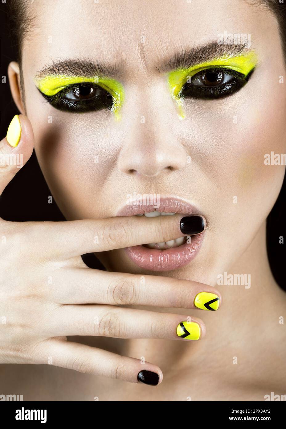 Close-up portrait of girl with yellow and black make-up, creative nail art disign. Beauty face. Photo shot in studio Stock Photo