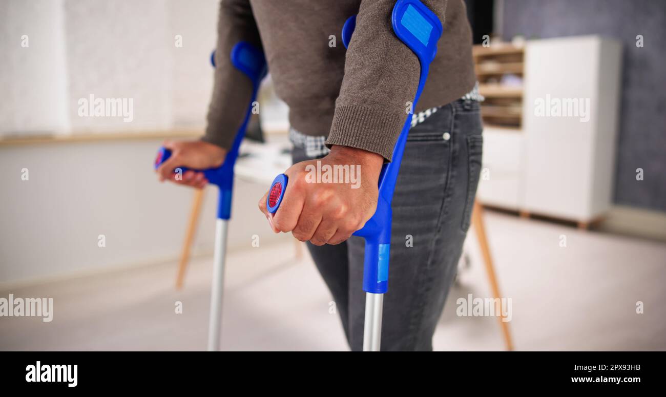 Worker With Crutches At Workplace Or Office. Rehabilitation Benefits
