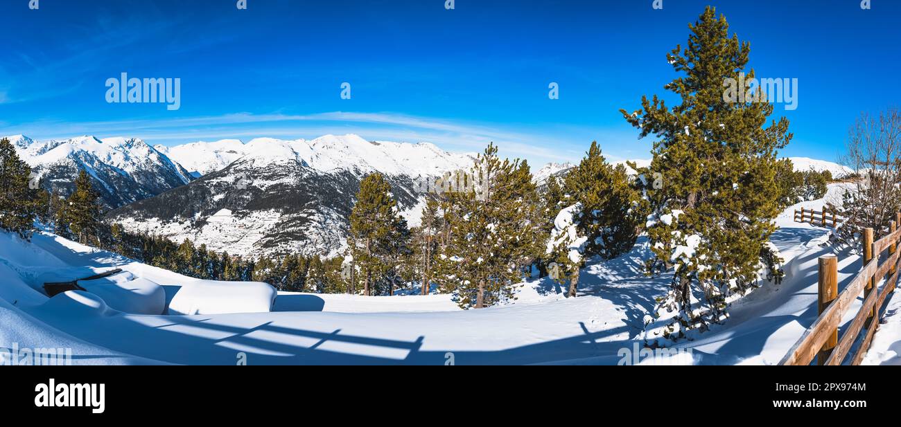 Panoramic view on ski shelters covered in fresh snow, snow capped mountains and green pine forest in Andorra, El Tarter, Pyrenees Mountains range Stock Photo