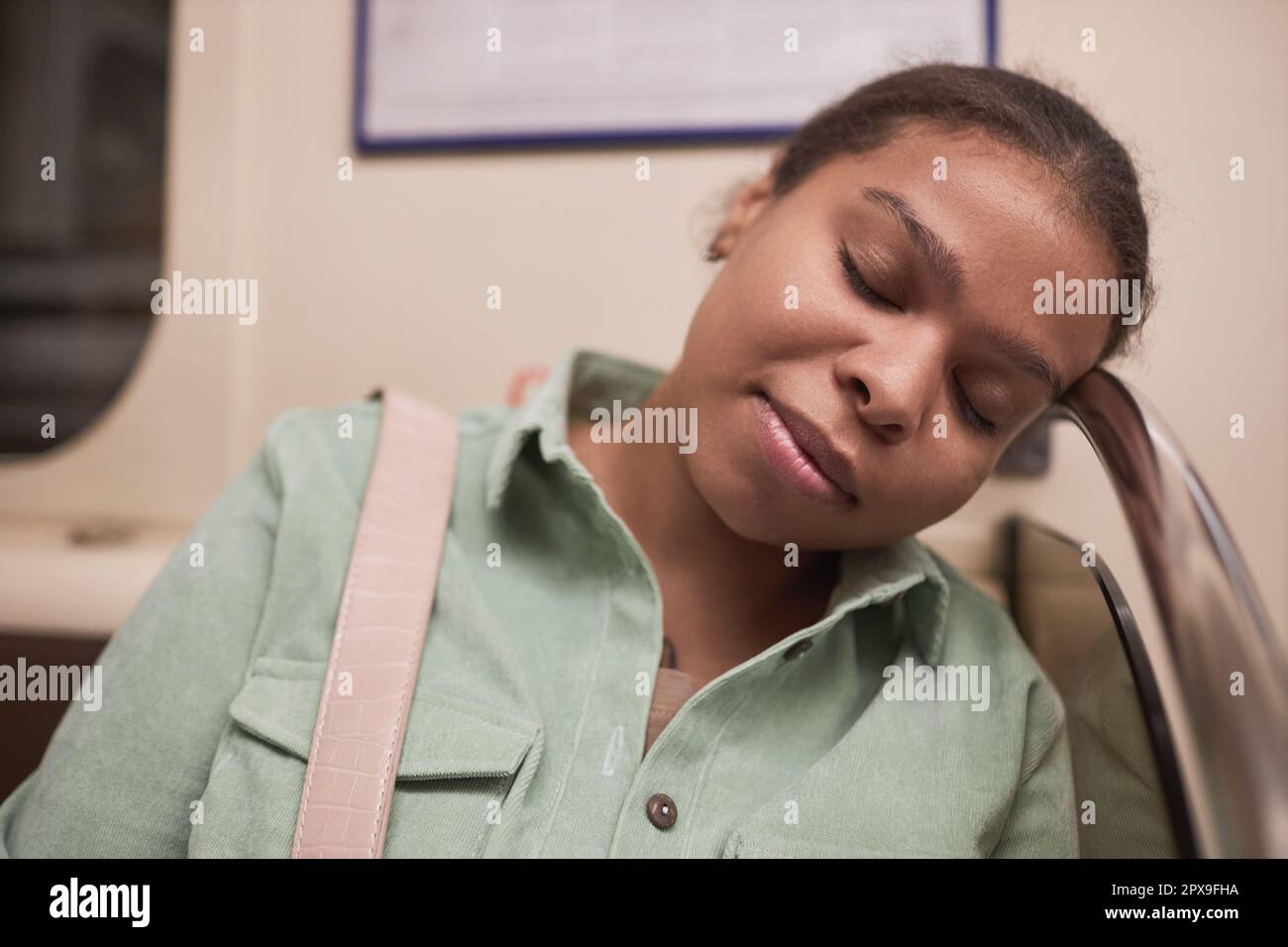 African American young woman sleeping in subway car during her journey