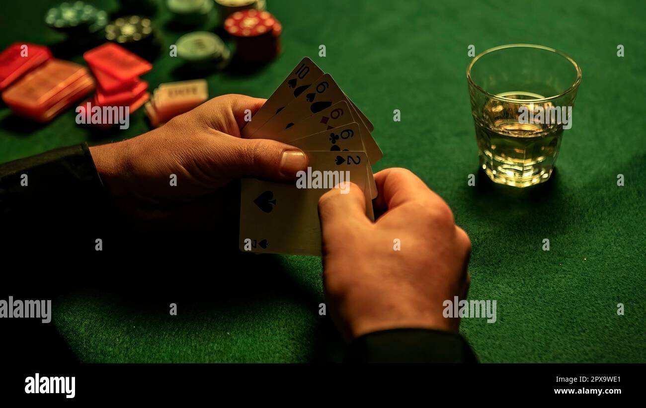 https://c8.alamy.com/comp/2PX9WE1/hands-closeup-holding-poker-cards-with-a-whiskey-glass-and-poker-chips-scattered-on-the-green-textured-table-2PX9WE1.jpg
