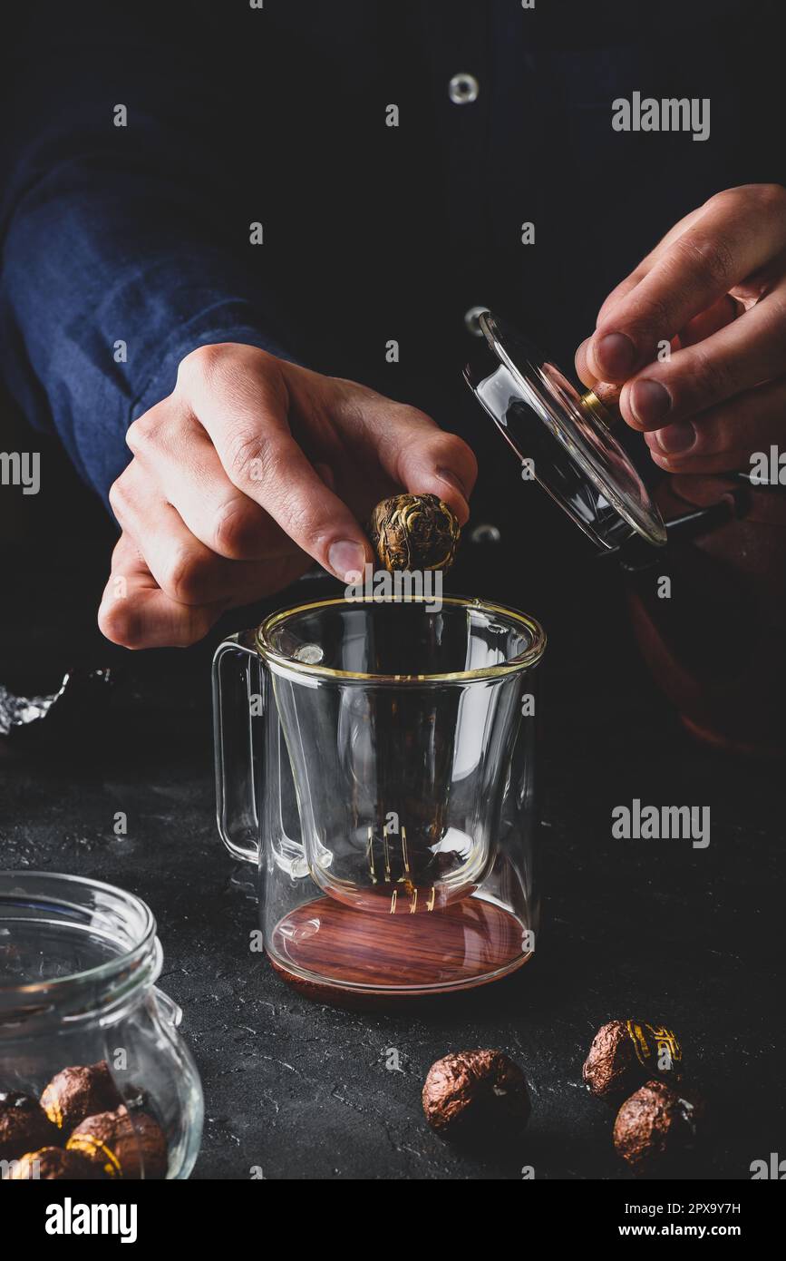 Steeping tea. Putting tea leaves into glass mug Stock Photo