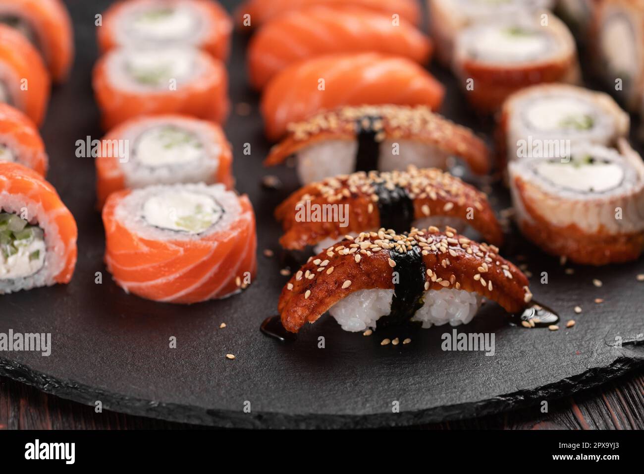 Large sushi set from top on black background. Assortment of various