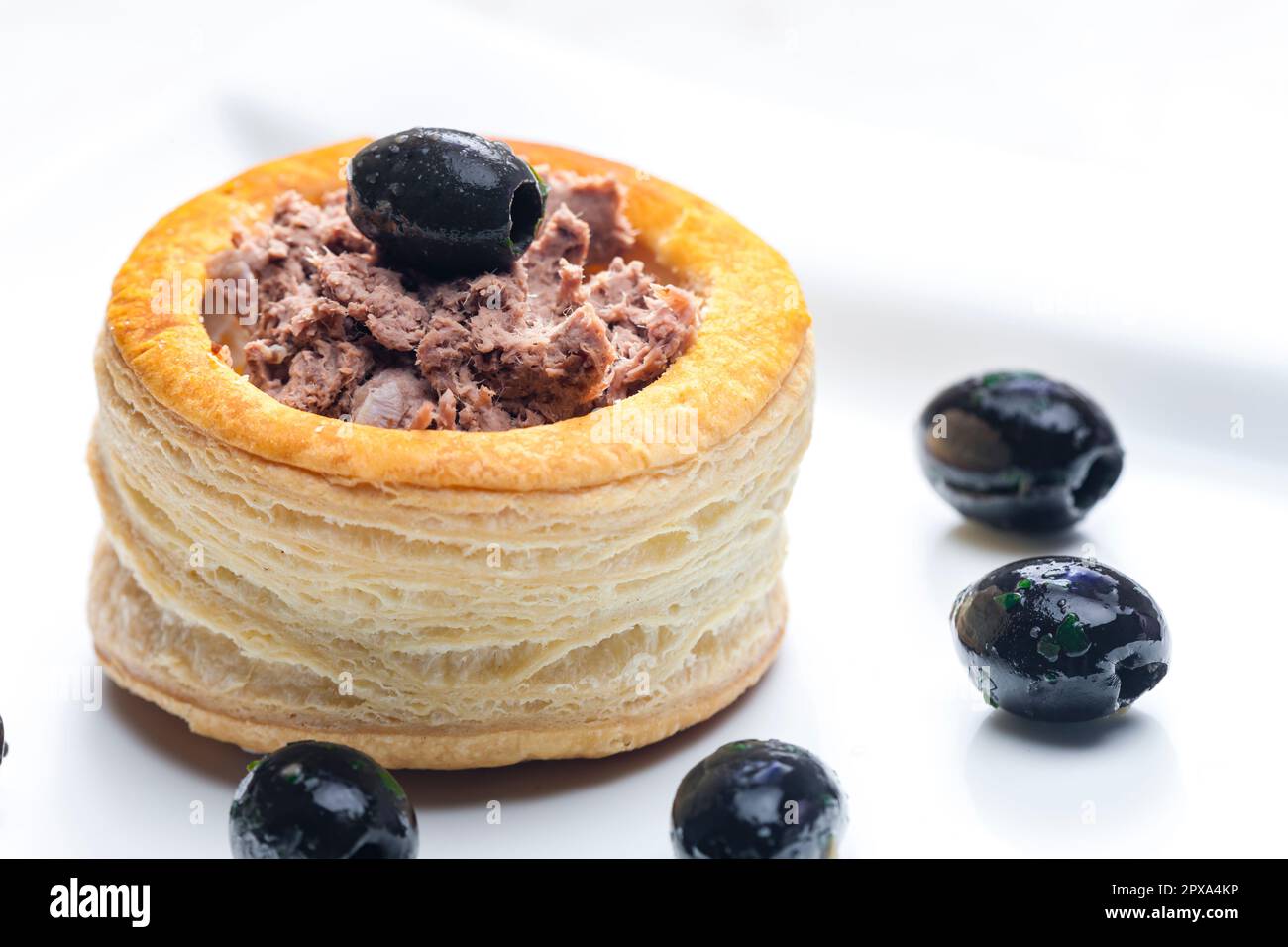 puff pastry filled with terrine served with black olives Stock Photo