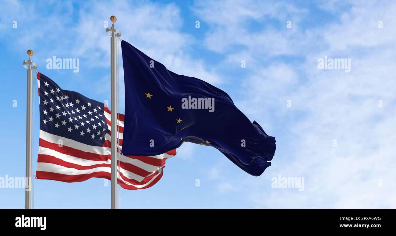 Alaska state flag waving alongside the national flag of the United States on a sunny day. Alaska flag is blue with Big Dipper and Polaris stars. Reali Stock Photo
