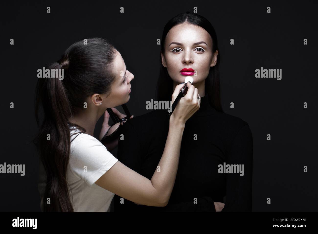 Two beautiful girls on a photo shoot to apply makeup to the face ...