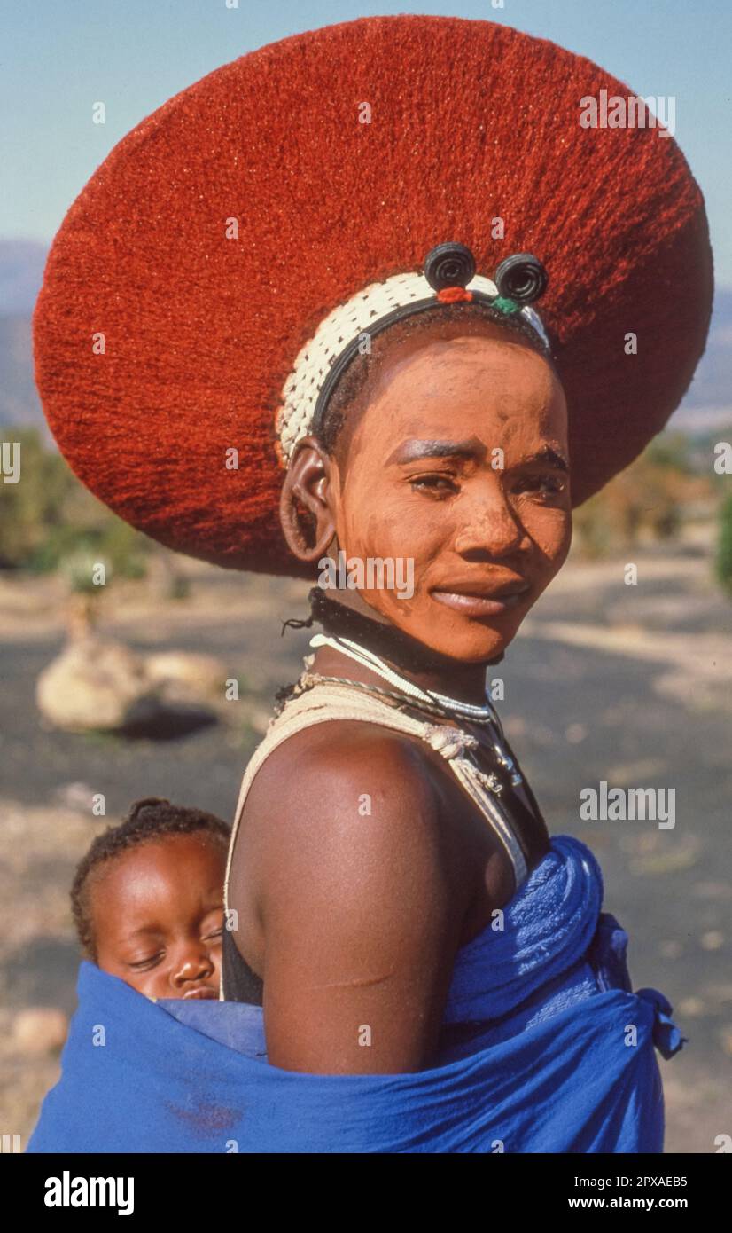 KWAZULU-NATAL, SOUTH AFRICA - MAY 2, 2023: Portrait of a beautiful Zulu woman, with her baby, in traditional dress and wearing an isicholo hat. Stock Photo