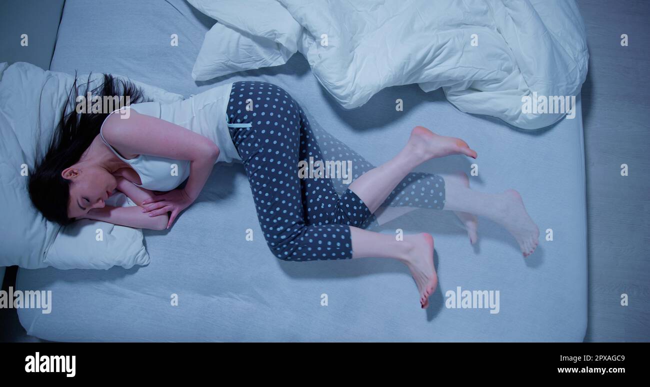 Woman With RLS Restless Legs Syndrome. Sleeping In Bed Stock Photo